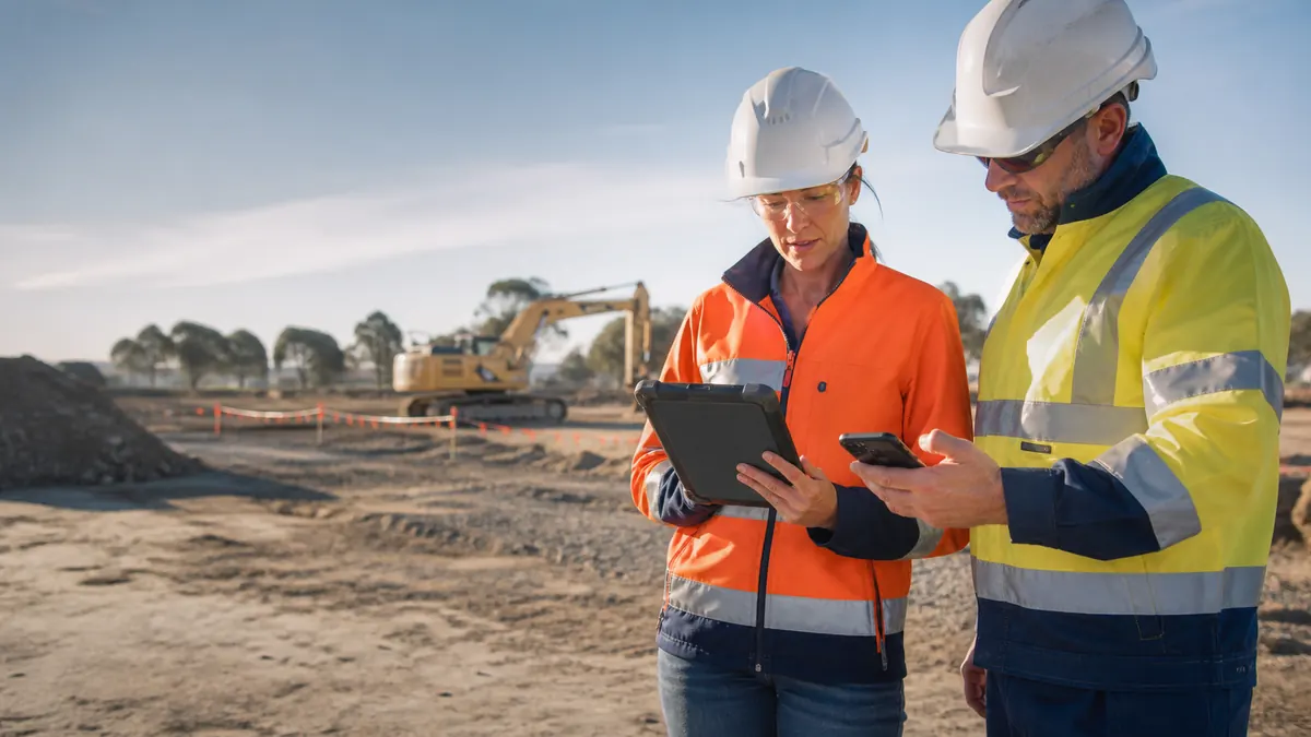 Two construction workers reviewing site attendance and location information on mobile devices